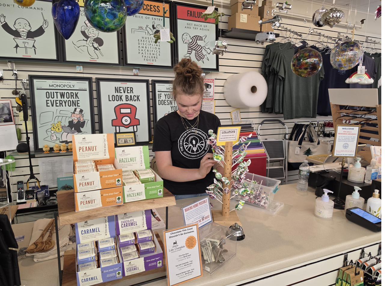 A young person stocking a display of products at the CES store counter.